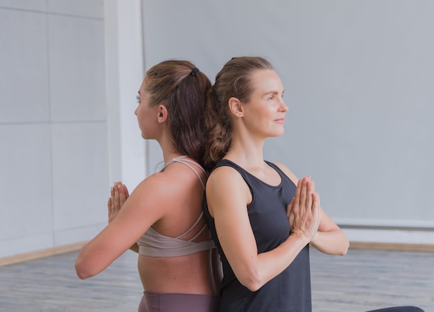 Due giovani donne a praticare yoga in palestra