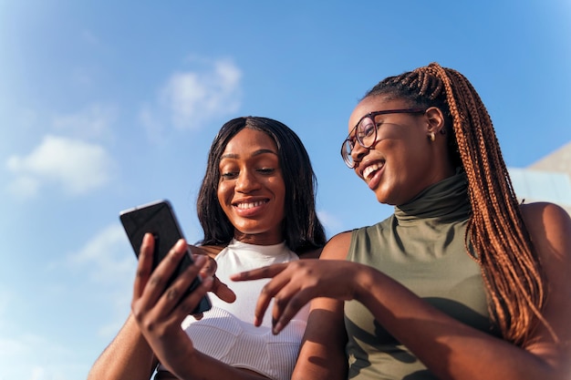 Due giovani donne africane che si divertono a guardare il telefono cellulare, il concetto di gioventù e la tecnologia della comunicazione, lo spazio della copia per il testo