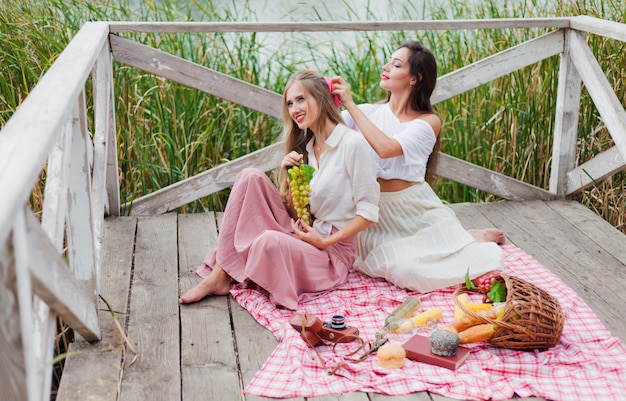 Due giovani donne allegre fanno un picnic all'aperto in una giornata estiva.