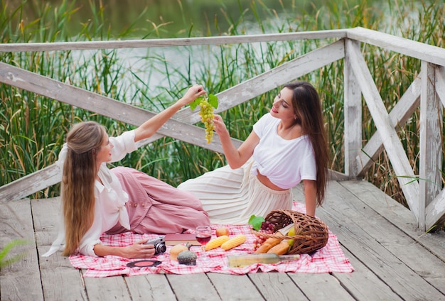 Due giovani donne allegre fanno un picnic all'aperto in una giornata estiva.