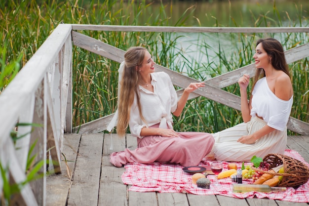 Due giovani donne allegre fanno un picnic all'aperto in una giornata estiva.