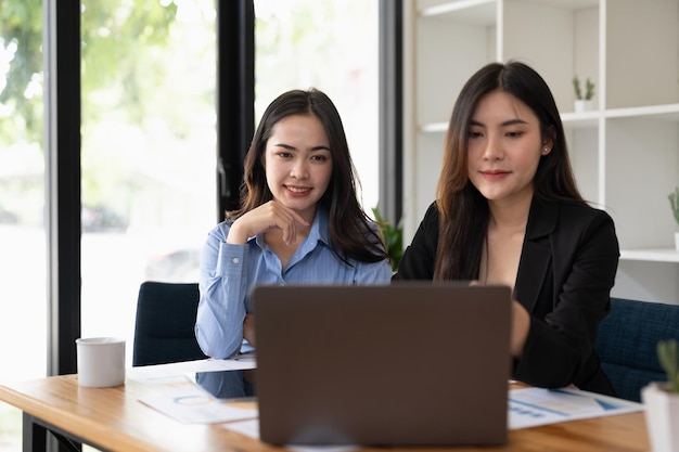 Due giovani donne asiatiche che lavorano al computer portatile in ufficio