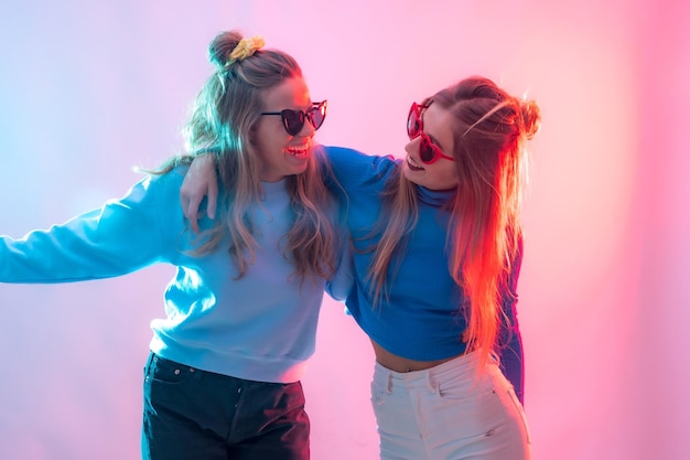 Due giovani donne caucasiche bionde che ballano in discoteca sorridendo e divertendosi