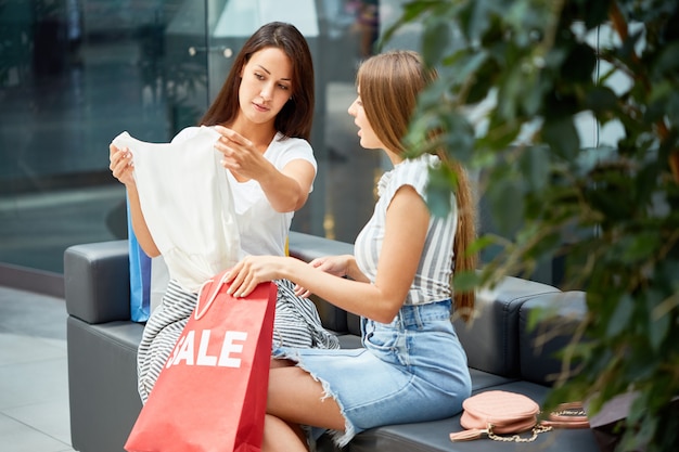 Due giovani donne che acquistano in vendita