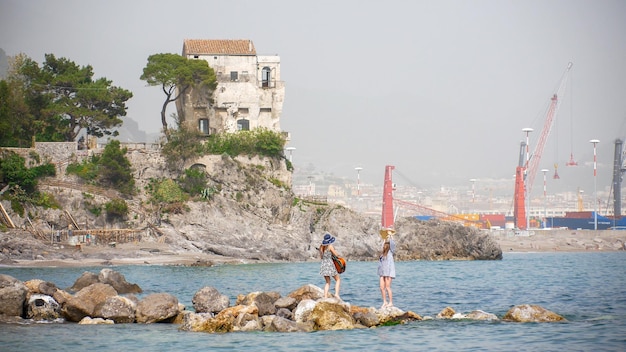 Due giovani donne che ballano sugli scogli del mare e suonano la chitarra