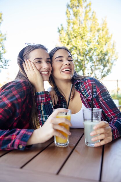 Due giovani donne che bevono succo e limonata nel parco