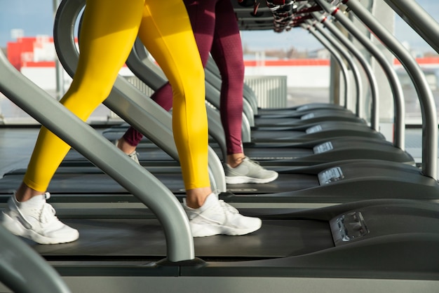 Due giovani donne che corrono sul tapis roulant in palestra