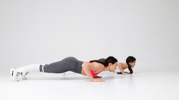 Due giovani donne che fanno esercizio di pushup in studio