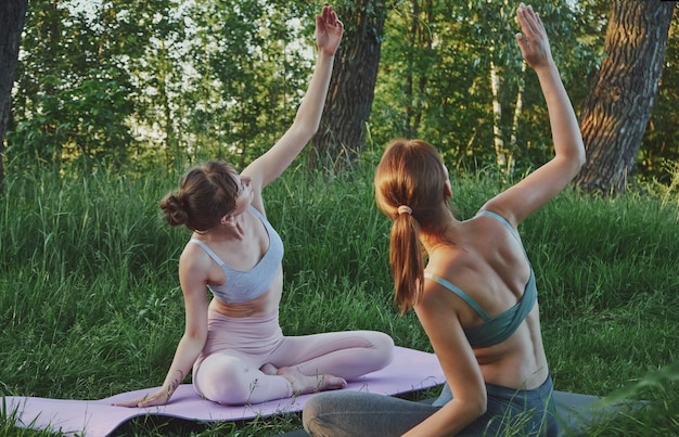 Due giovani donne che fanno yoga all'aperto assistenza sanitaria mentale