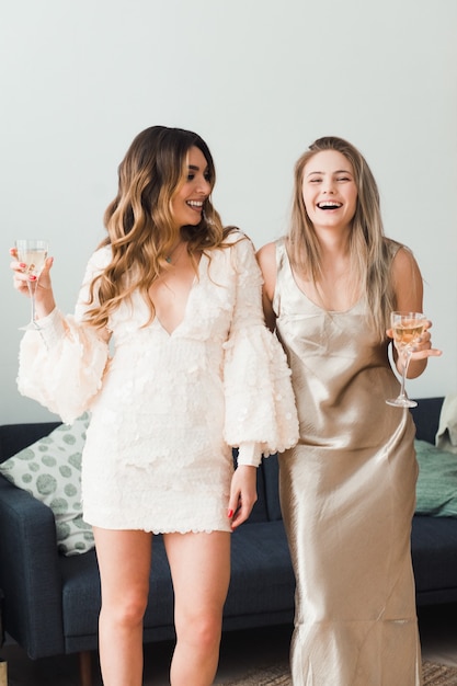 Due giovani donne che festeggiano il capodanno o il compleanno in casa con bicchieri di vino