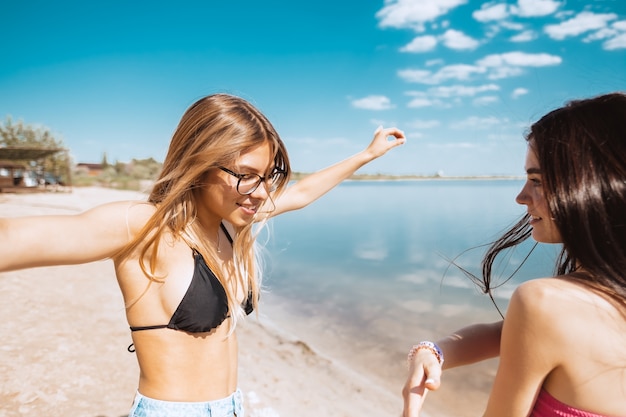 Due giovani donne che hanno divertimento sulla spiaggia in una calda giornata di sole.