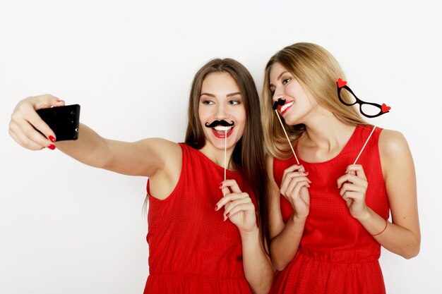 Due giovani donne che indossano un abito rosso che si fanno selfie con il cellulare