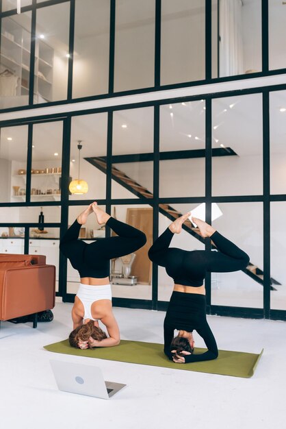 Due giovani donne che lavorano al chiuso facendo esercizio di yoga sulla stuoia