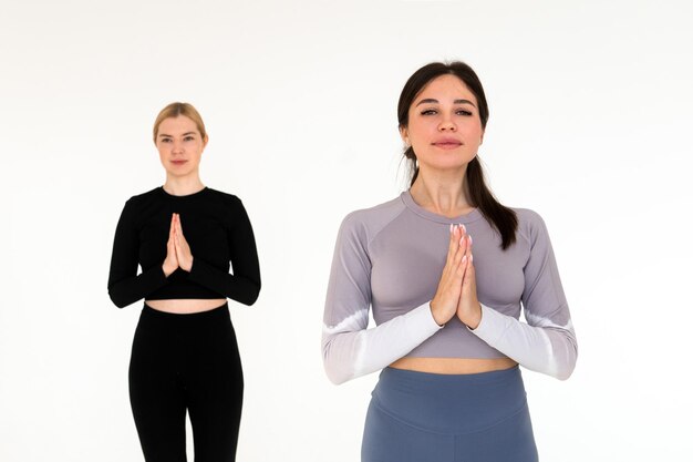 Due giovani donne che praticano yoga su sfondo bianco serenità e concetto di consapevolezza