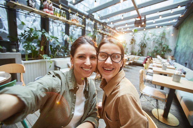 Due giovani donne che prendono selfie al caffè terrazza