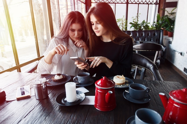 Due giovani donne che prendono selfie con smart phone nel ristorante