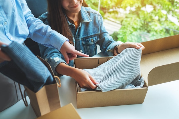 Due giovani donne che ricevono e aprono una cassetta postale di vestiti a casa per la consegna e il concetto di shopping online