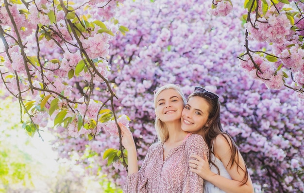 Due giovani donne che si rilassano nelle ragazze primaverili dei fiori di sakura