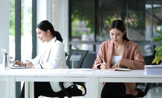 Due giovani donne d'affari asiatiche discutono con il nuovo progetto di avvio La presentazione dell'idea analizza la pianificazione e le statistiche finanziarie e il mercato degli investimenti in ufficio