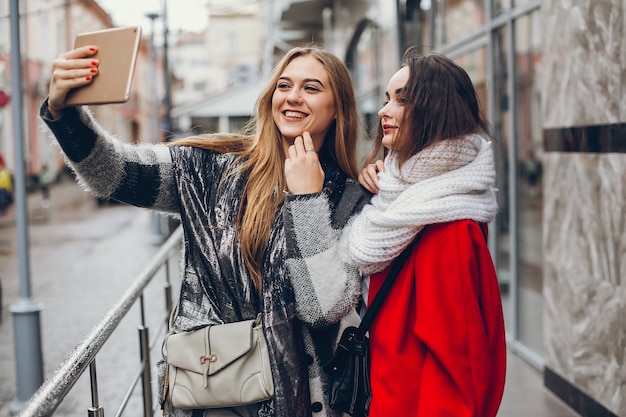 Due giovani donne d&#39;affari eleganti in piedi in una città d&#39;autunno e utilizzare il tablet