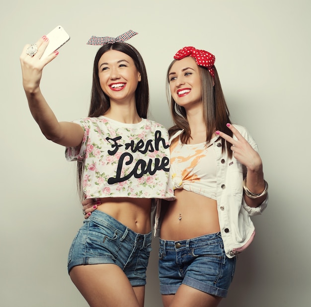 Due giovani donne divertenti che prendono selfie con il telefono cellulare