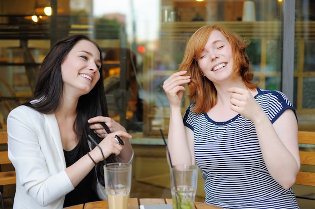 Due giovani donne divertirsi al caffè all'aperto