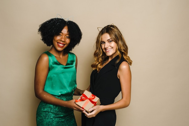 Due giovani donne felici di diverse nazionalità stanno tenendo un regalo