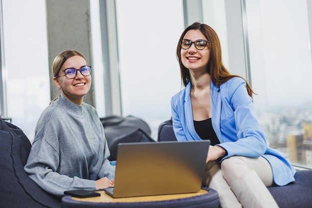 Due giovani donne freelance che lavorano a distanza nell'area salotto con un computer portatile Il concetto di lavoro a distanza