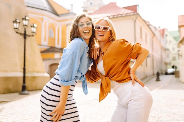 Due giovani donne in abiti estivi alla moda che posano sullo sfondo della strada Concetto di stile di vita