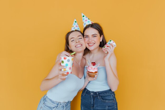 Due giovani donne in cappelli di compleanno che festeggiano il compleanno