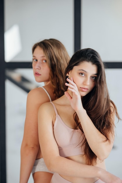 Due giovani donne in piedi indossando lingerie sguardo fiducioso alla fotocamera