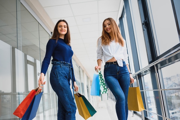 due giovani donne stanno camminando con le borse della spesa al centro commerciale