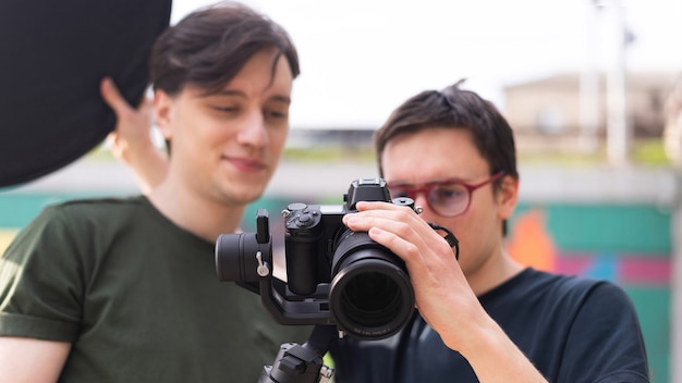 Due giovani fotografi sorridenti che esaminano la macchina fotografica su un treppiede al servizio fotografico