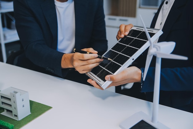 Due giovani ingegneri esperti nell'installazione di celle solari riunioni e discussioni sul lavoro pianificazione per l'installazione di pannelli solari fotovoltaici sul tetto nella sala uffici con piano di costruzione della fabbrica