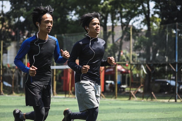 Due giovani maschi sportivi fanno jogging atleti in abbigliamento sportivo facendo allenamento nel parco mentre ascoltano digita