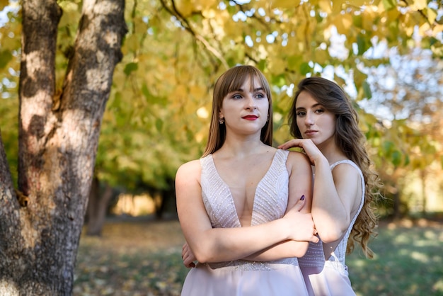 Due giovani principesse che indossano un bel vestito beige nel parco autunnale. Foto di moda.