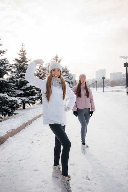 Due giovani ragazze atletiche che camminano e praticano sport in una giornata invernale di sole. Uno stile di vita sano.