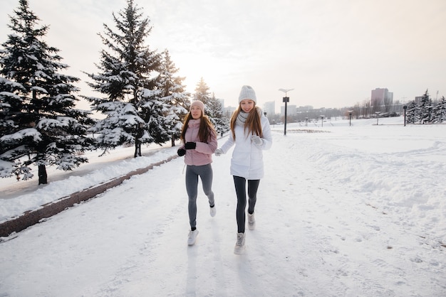 Due giovani ragazze atletiche che corrono nel parco in una giornata invernale di sole. Uno stile di vita sano.