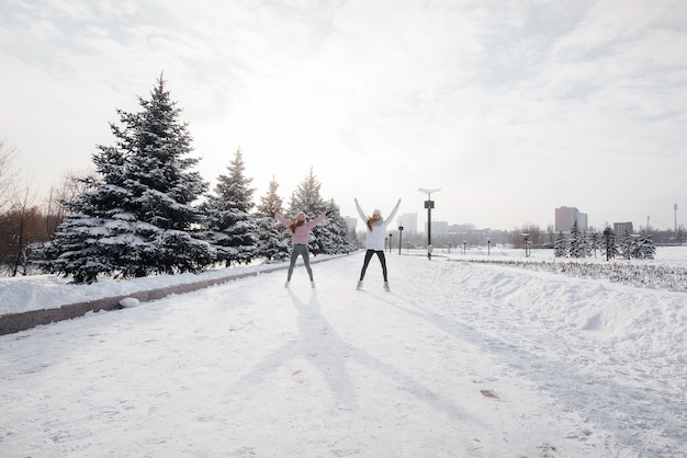 Due giovani ragazze atletiche fanno un riscaldamento prima di correre in una soleggiata giornata invernale. Uno stile di vita sano.
