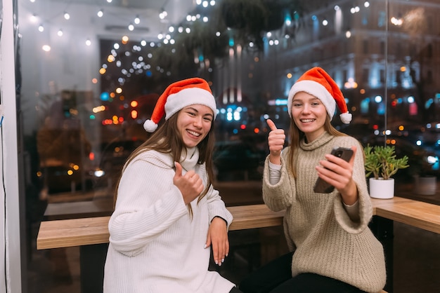 Due giovani ragazze che utilizzano smartphone al caffè