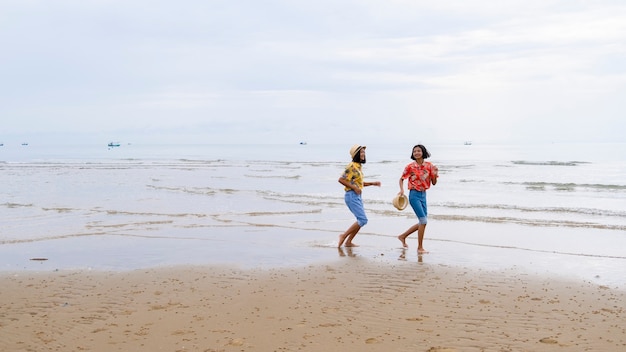 Due giovani ragazze indossano jeans e magliette colorate in esecuzione alla bellissima spiaggia.