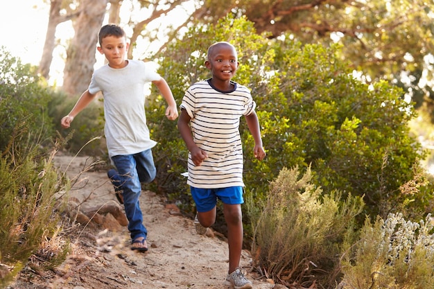 Due giovani ragazzi felici che corrono lungo un sentiero nel bosco