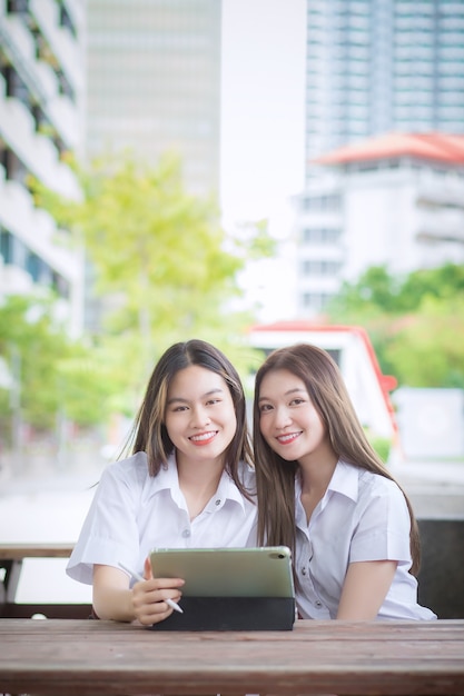 Due giovani studentesse asiatiche si consultano e usano un tablet per cercare informazioni