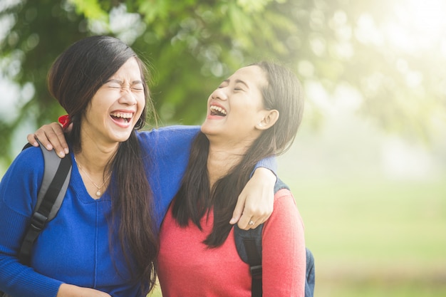 Due giovani studenti asiatici ridono, scherzando insieme
