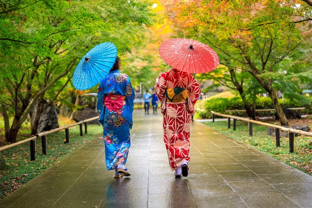 Due giovani turisti che indossano kimono rosso blu e ombrello hanno fatto una passeggiata nel parco nella stagione autunnale del Giappone