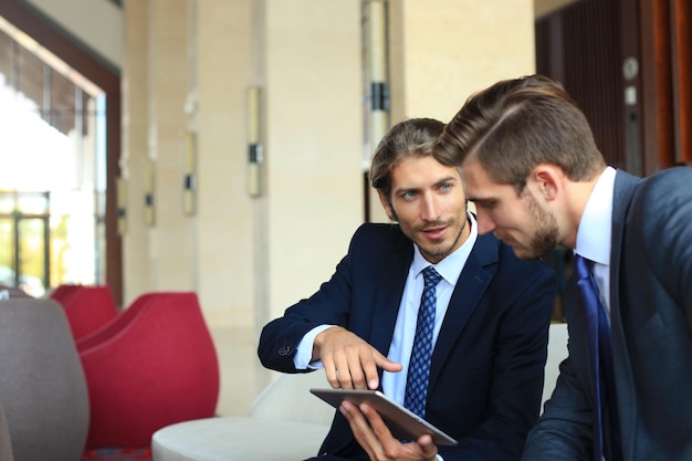 Due giovani uomini d'affari che utilizzano il touchpad alla riunione.
