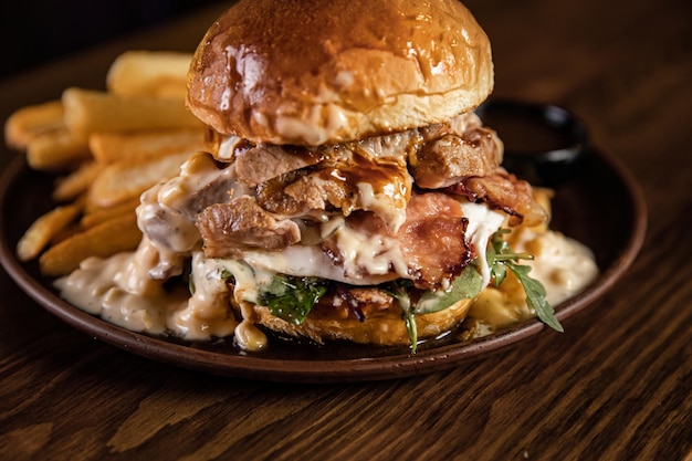 Due hamburger e patatine fritte su tavola di legno grande tortino da mezzo chilo con vero cheddar fuso e molta salsa