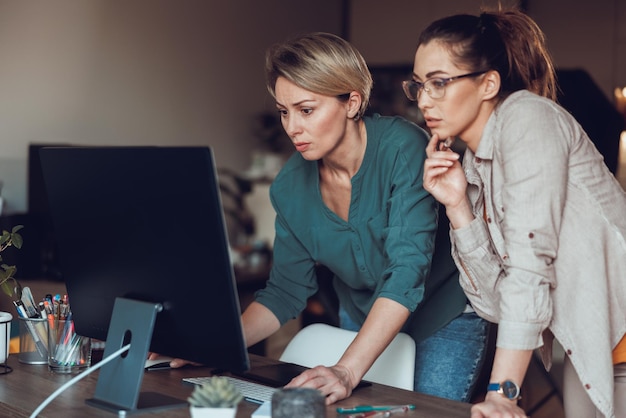 Due imprenditrici che sembrano premurose mentre lavorano insieme al computer, facendo progetti dall'home office.