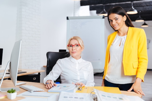 Due imprenditrici sorridenti che lavorano insieme sul computer al tavolo in ufficio