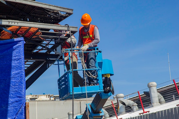 Due industrie maschili che lavorano in alto in un sistema di cablaggio elettrico dell'ascensore del braccio